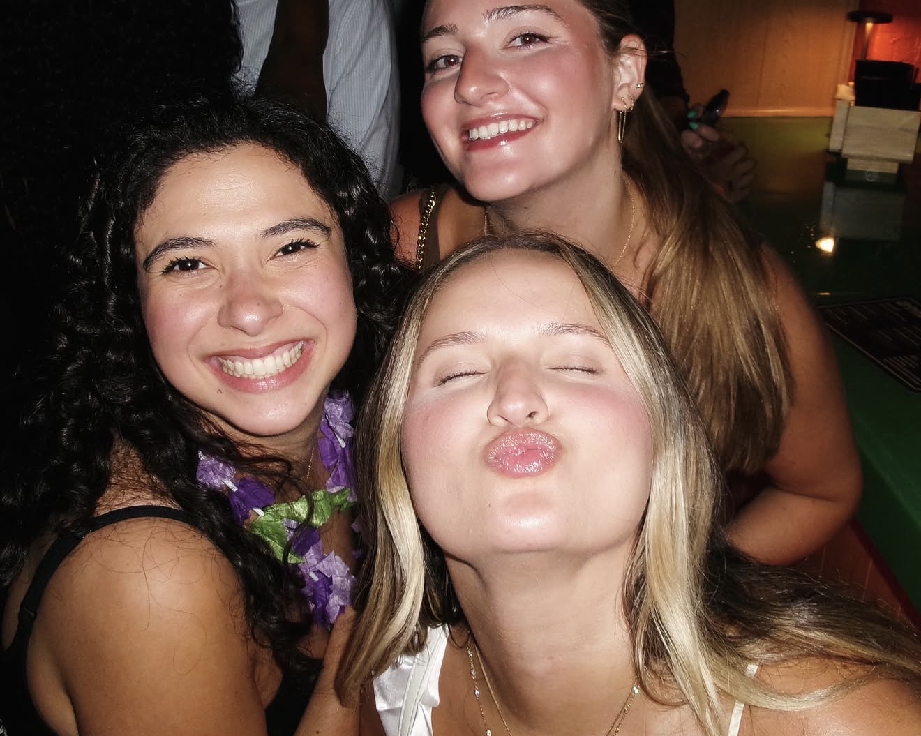 Layza and two friends squeezing together for a flash selfie at the bar