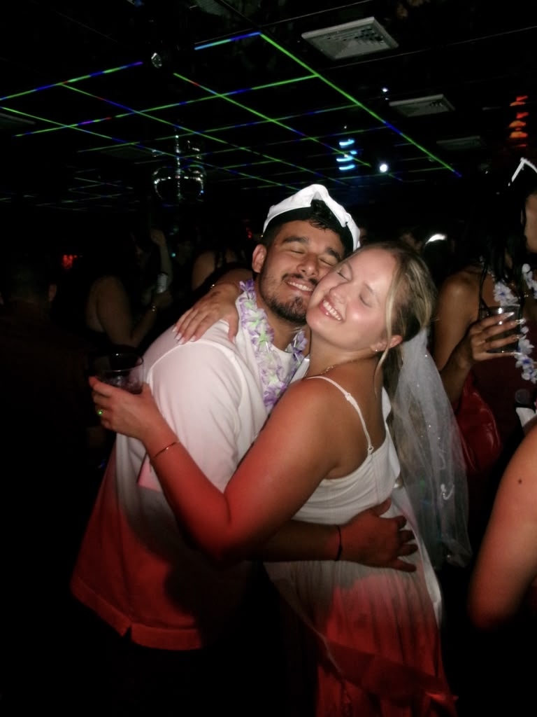 Matheus and Layza hugging on the dance floor under laser lights