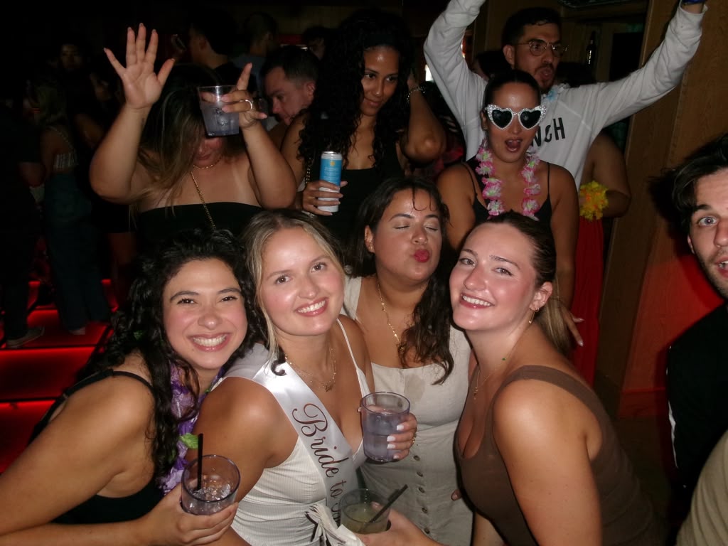 Layza in her bride-to-be sash surrounded by friends in the red-lit club