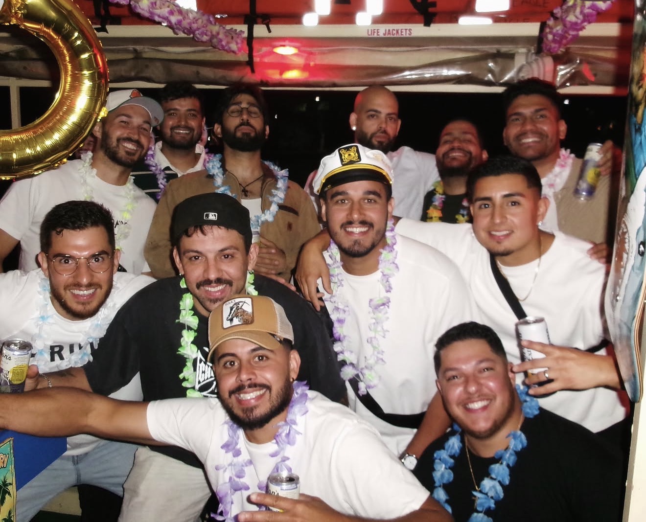 Matheus and the guys in leis and a captain's hat on the boat