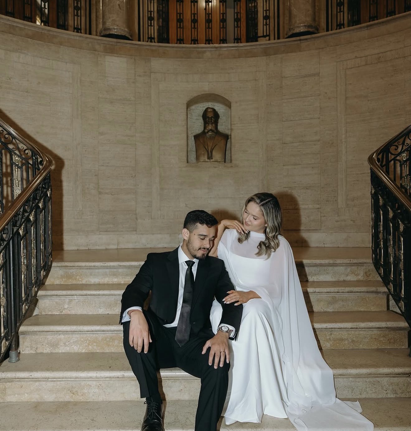 Matheus and Layza seated together on the grand staircase, elegant and close