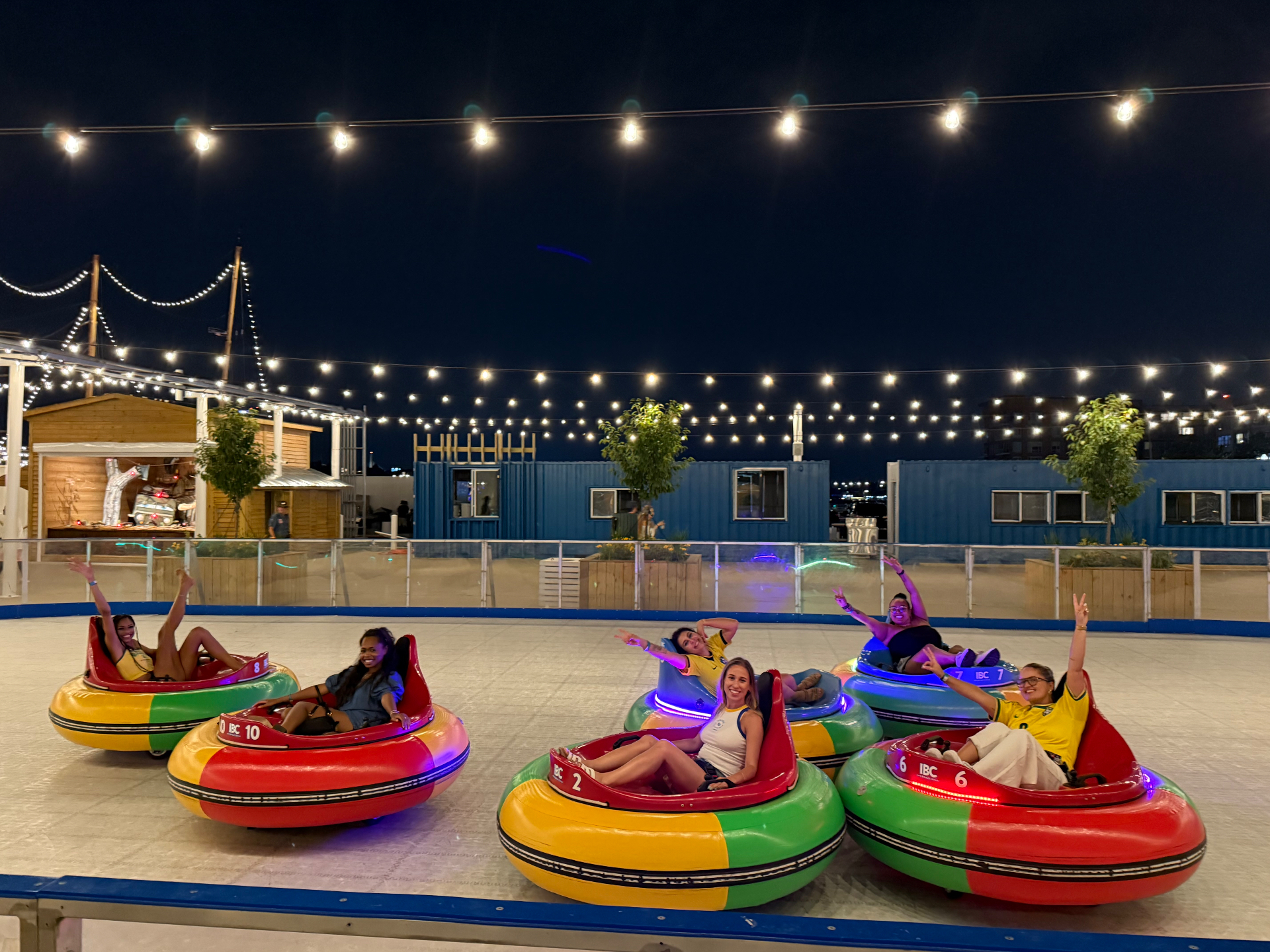 Friends riding bumper cars under string lights at night