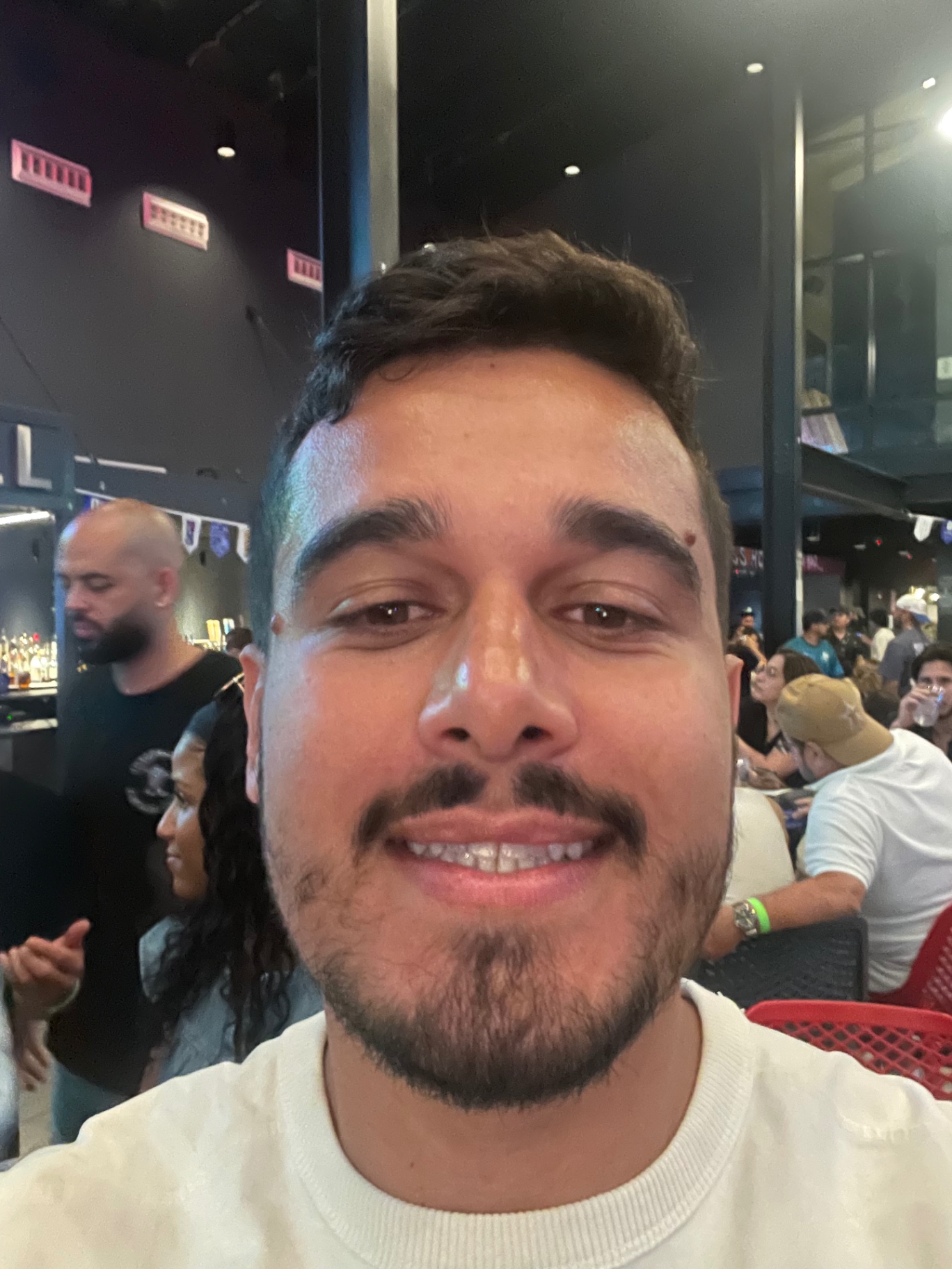 Matheus smiling in a crowded bar