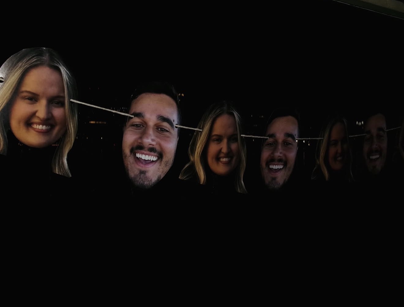 A garland of cut-out faces of the couple and their friends strung in the dark