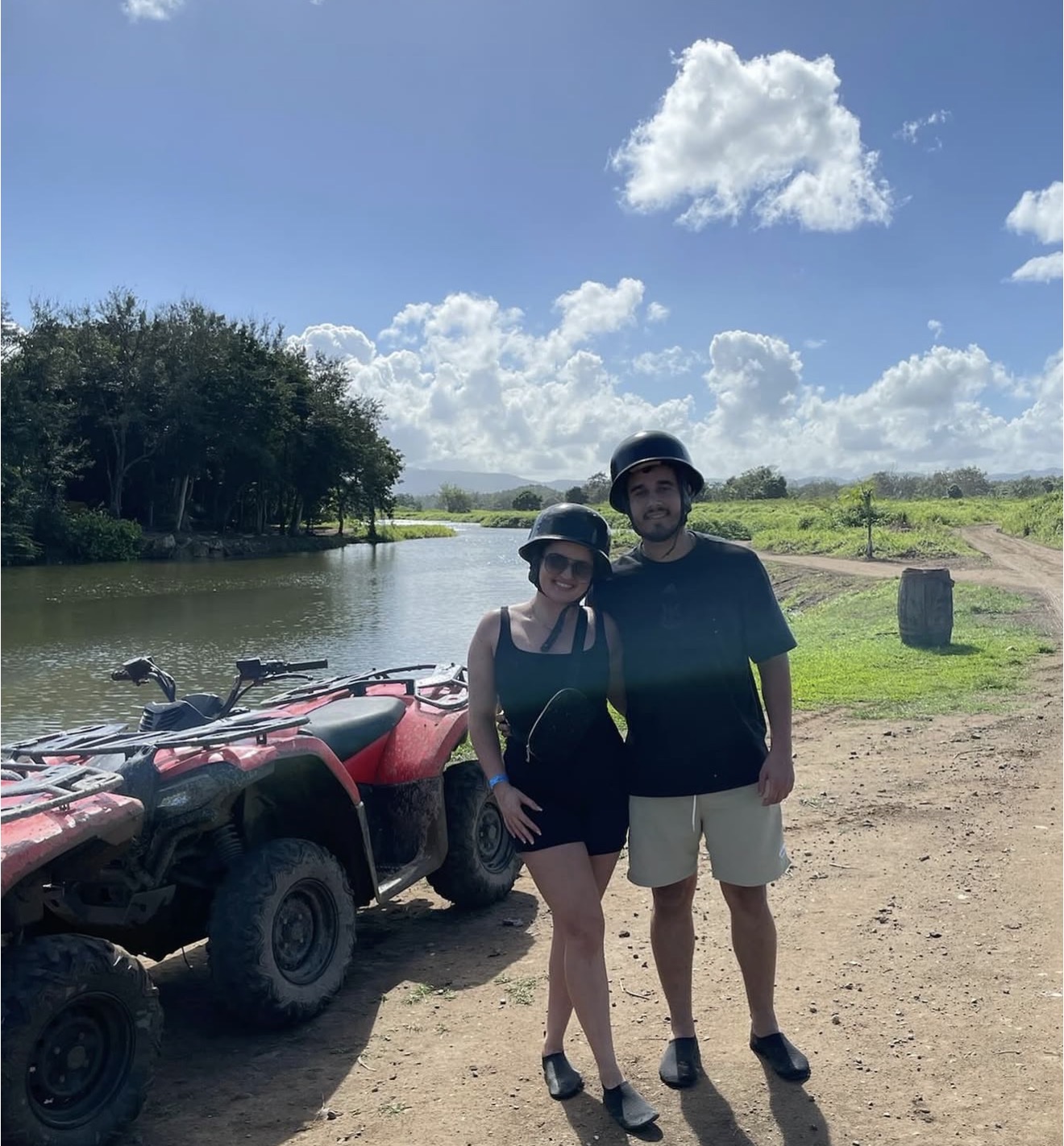 Matheus and Layza in helmets beside an ATV by the river